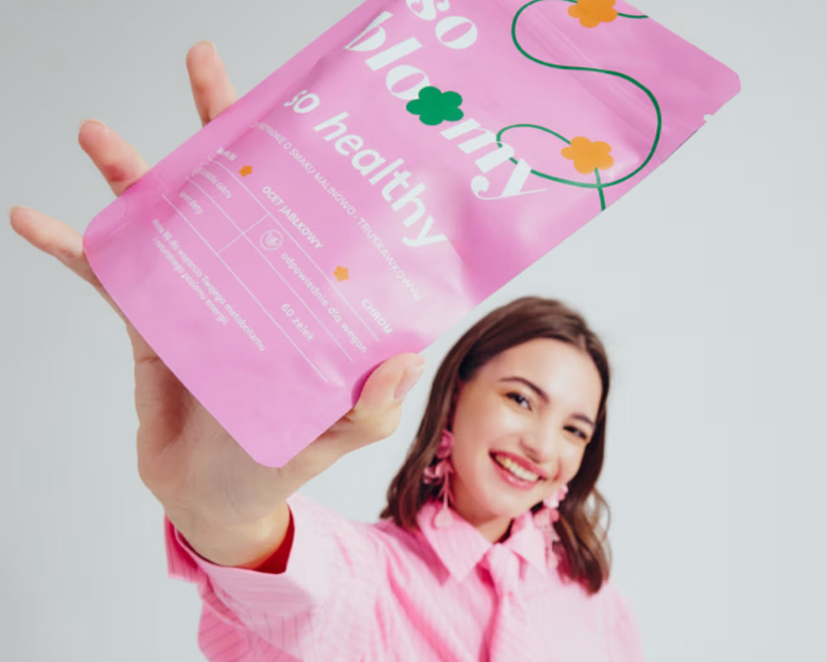 uśmiechnięta dziewczyna trzyma w górze opakowanie żelek z octem jabłkowym so healthy od so bloomy