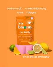 żelki so lovely o smaku owoców cytrusowych, ze składnikami: koenzym Q10, kwas hialuronowy, cynk, biotyna. Pomarańczowe opakowanie żelek ułożone na różowym kwiatku, poniżej cytryny i limonki.