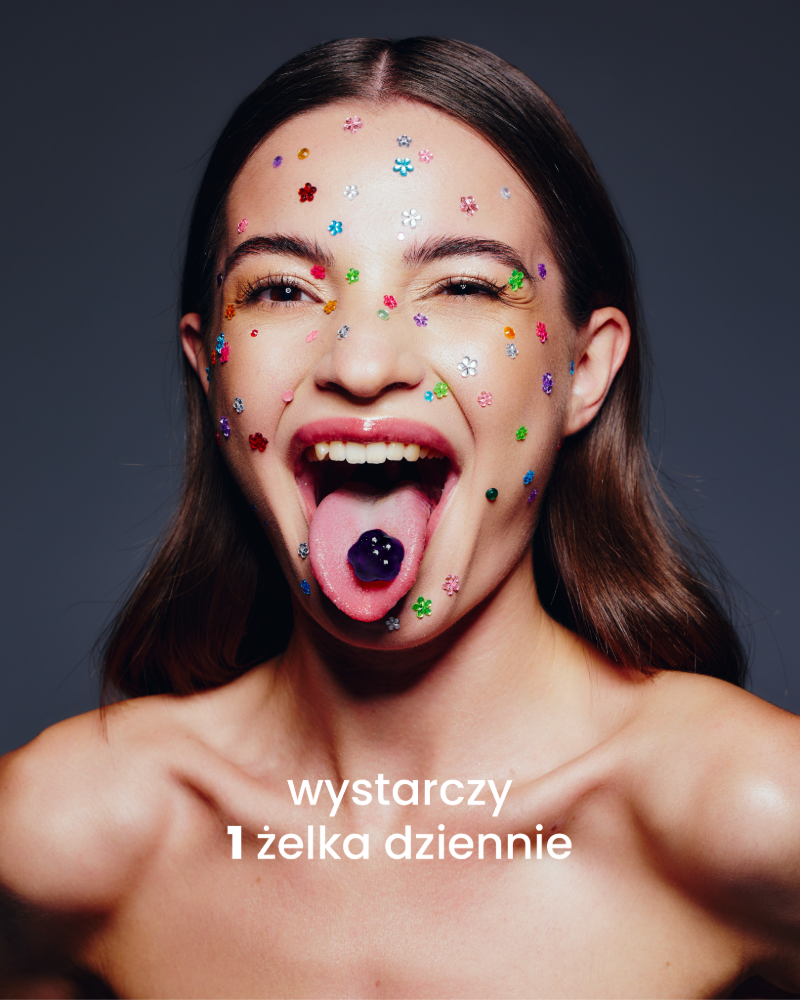 Dziewczyna z przyklejonymi małymi kolorowymi kwiatkami na twarzy wystawia język, na którym jest fioletowa żelka so bloomy. Poniżej napis: wystarczy 1 żelka dziennie.