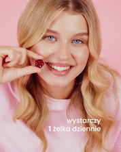 Uśmiechnięta dziewczyna trzymająca żelka so healthy w kształcie różowego kwiatka. Poniżej napis: wystarczy 1 żelka dziennie.