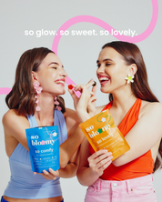 Dwie uśmiechnięte dziewczyny jedzą wegańskie żelki so bloomy. Jedna z nich trzyma opakowanie żelek so comfy, druga trzyma opakowanie so lovely.