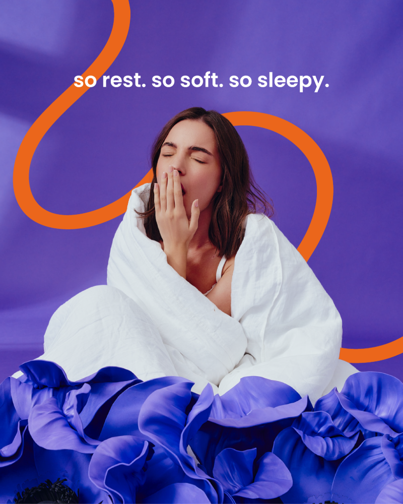 Ziewająca dziewczyna otulona pościelą. W dolnej części niebieskie kwiaty. U góry napis: so rest. so soft. so sleepy.