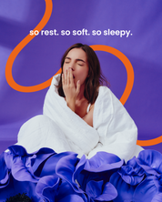 Ziewająca dziewczyna otulona pościelą. W dolnej części niebieskie kwiaty. U góry napis: so rest. so soft. so sleepy.